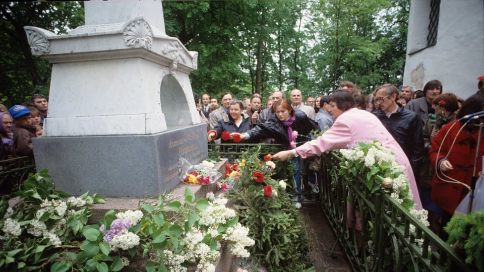 Menschen legen Blumen am Grab von Alexander Puschkin ab. 