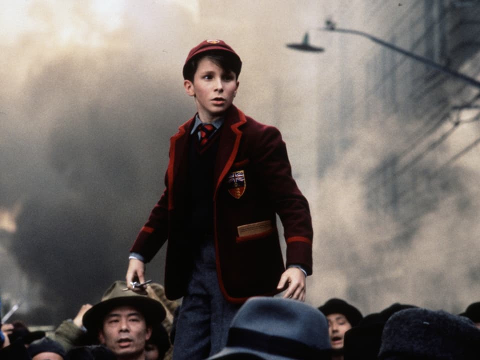 Ein Junge mit Mütze in rotem Jackett.