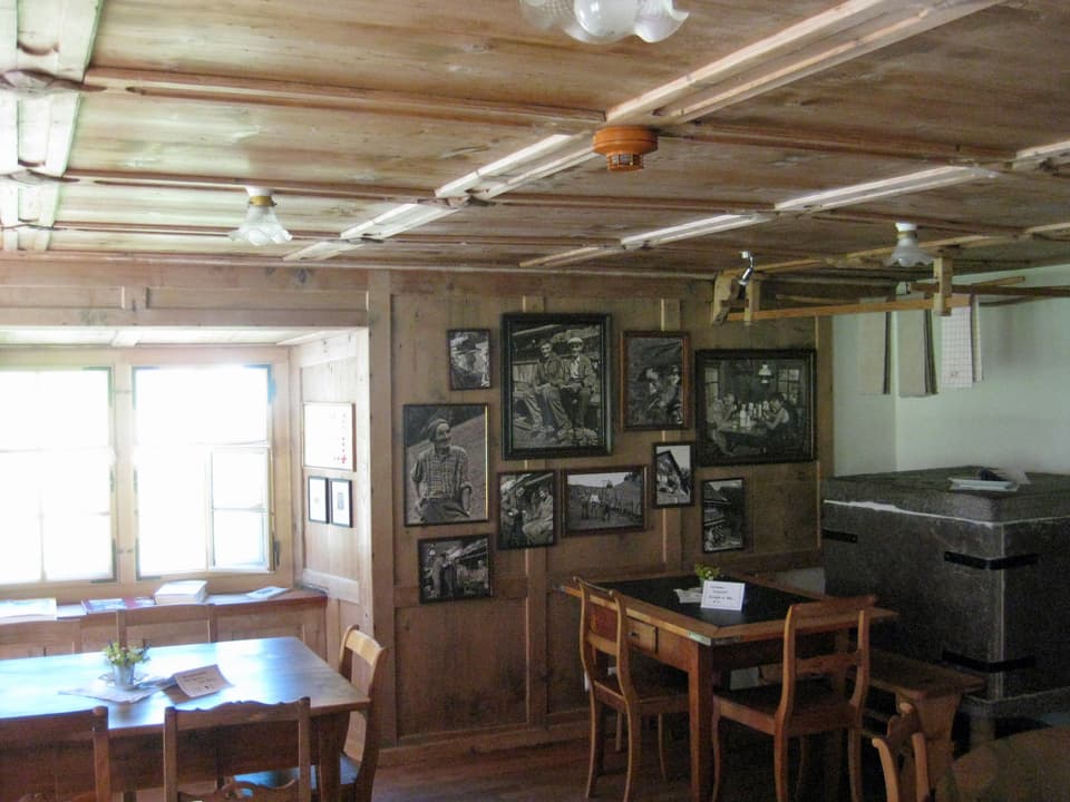Holzstube mit alten Tischen und Bildern an den Wänden