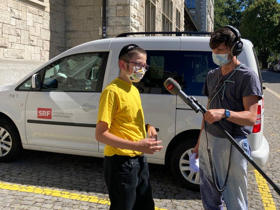 Moderator Gabriel Crucitti und Moischi stehen zusammen vor der jüdisch-orthodoxen Schule