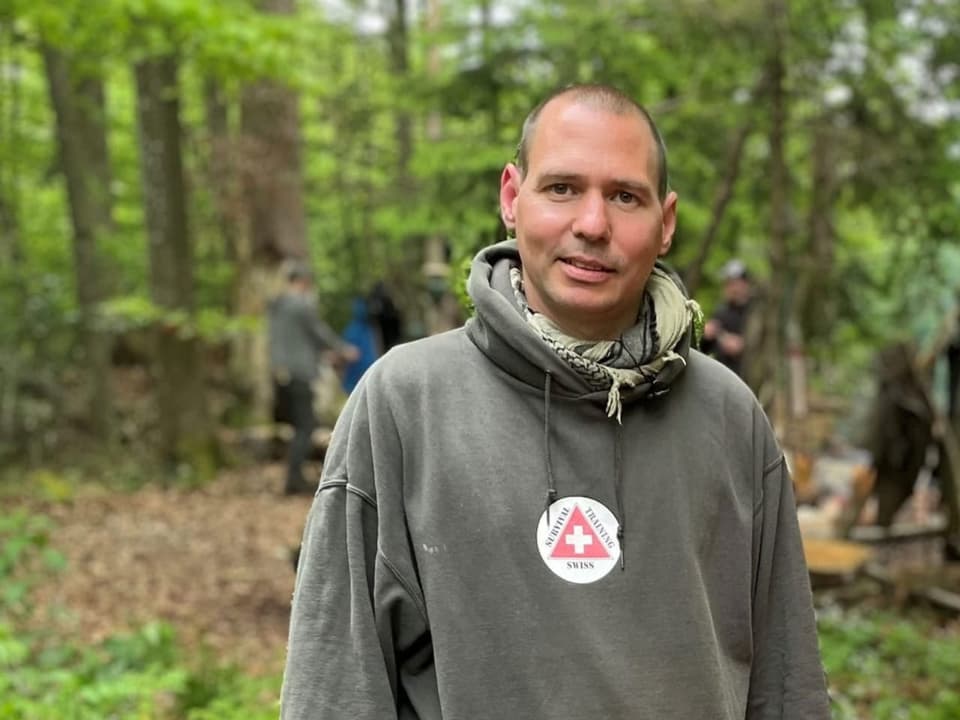 Mann mit Kapuzen-Pullover draussen im Wald.