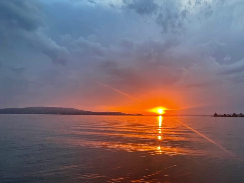 Sonnenuntergang über dem See mit Gewitterresten