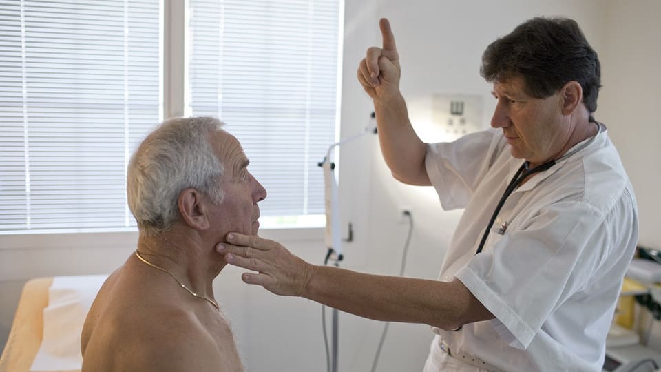 Arzt untersucht den Hals eines älteren Patienten im Untersuchungszimmer.
