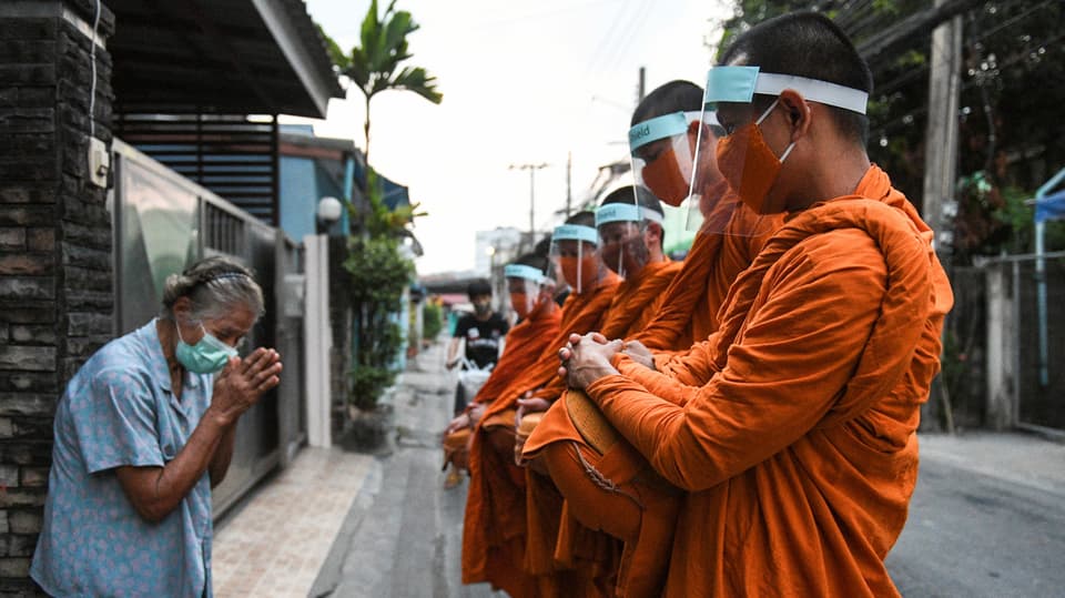  Buddhistische Mönche sammeln Almosen mit Gesichtsschutz. 