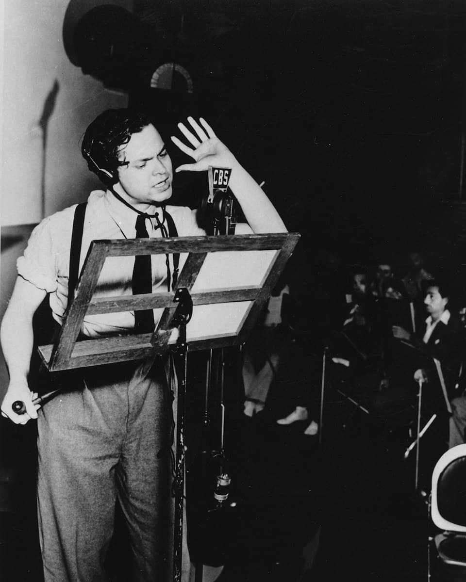 Orson Welles vor einem Notenständer und Mikrofon in einem New Yorker Studio.