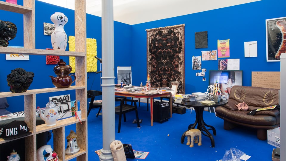 Zimmer mit blauen Wänden, vollgestopft mit Gegenständen.