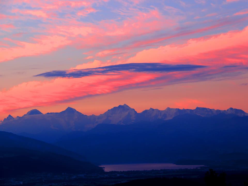Farbenfrohe Morgenstimmung mit See und Alpen.