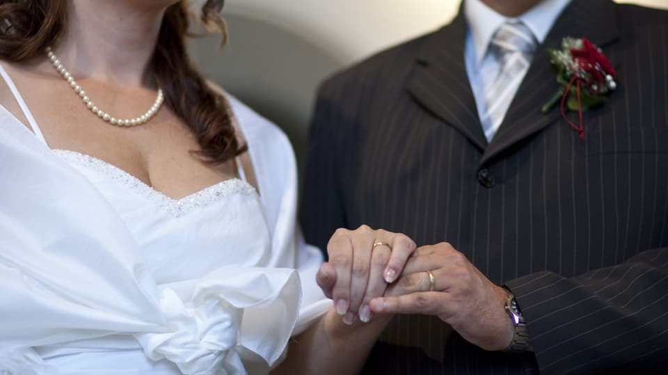 Ein Mann und eine Frau halten sich die Hände und zeigen ihre Eheringe.