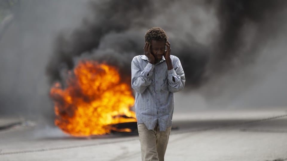 Mann vor brennender Barrikade in Port-au-Prince