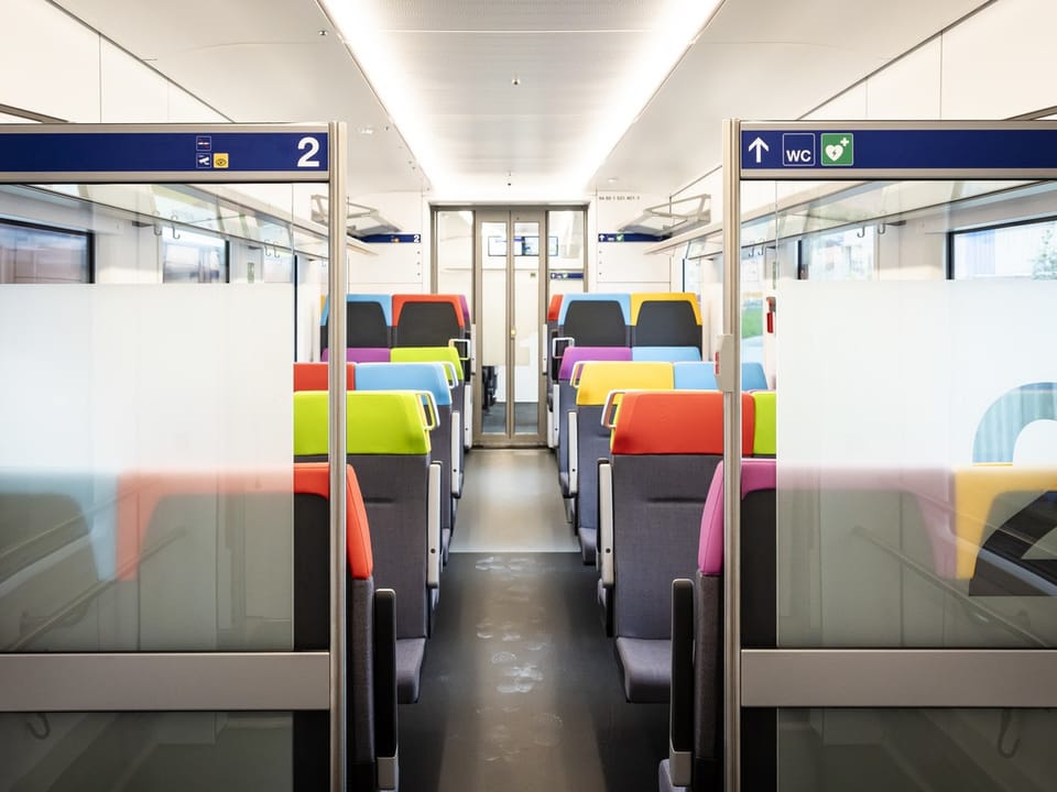 Innenraum eines modernen Zuges mit bunten Sitzen.