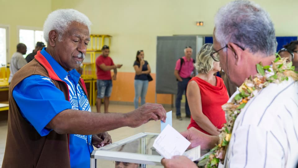 Zwei Männer legen ihre Stimmzettel in die Wahlurnen.