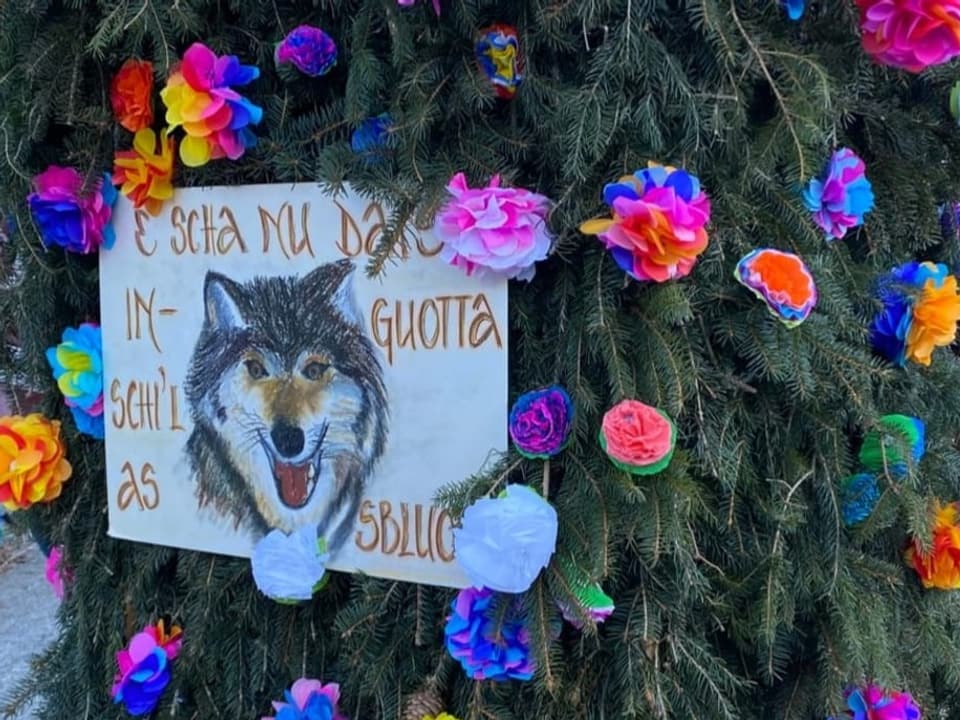 Papierblumen Ein Wagen mit Tannenkries ist mit farbigen Papierblumen dekoriert. In der Mitte hängt ein Bild von einem Wolf.