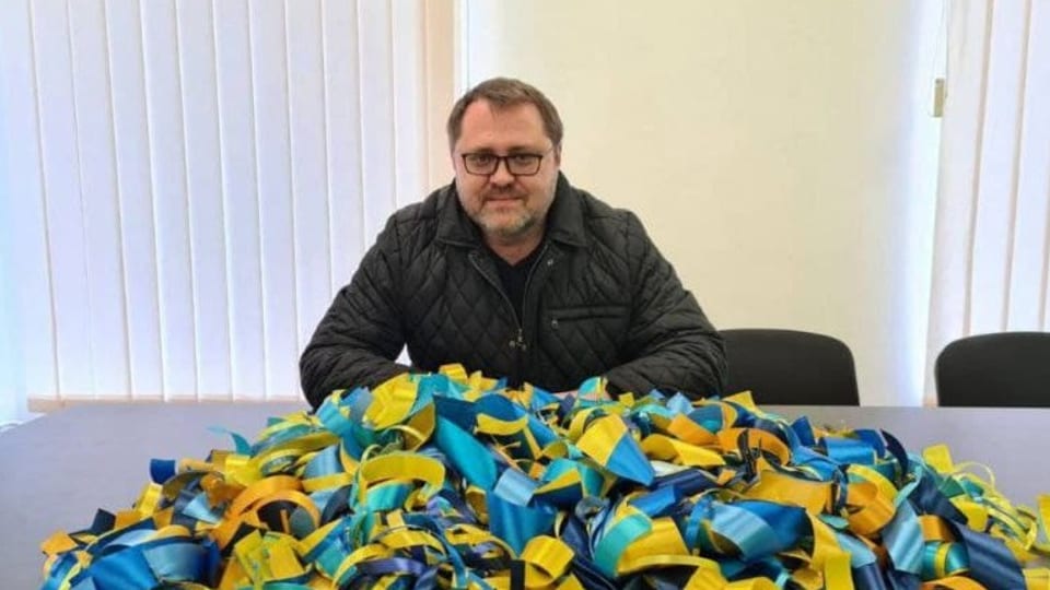 Juri Sobolewski, vor ihm auf dem Tisch liegen blau-gelben Schleifen