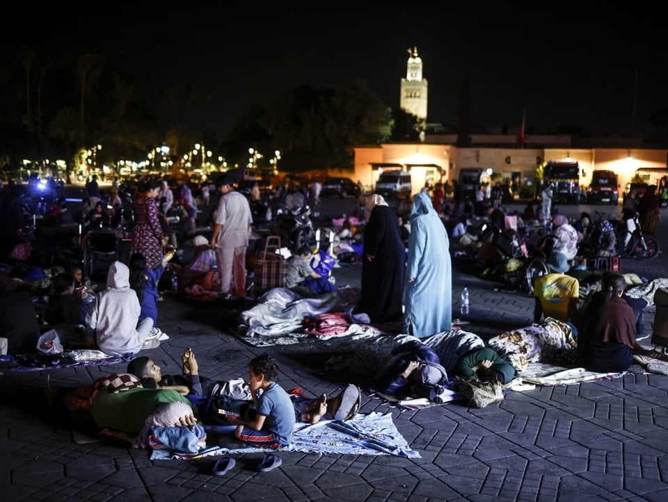 Familien sitzen in Marrakesch auf Decken am Boden.