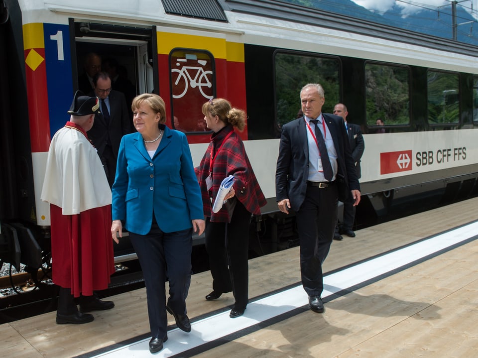Angela Merkel steigt in Pollegio aus dem VIP-Zug, im Hinergrund ein Standesweibel und weitere Gäste