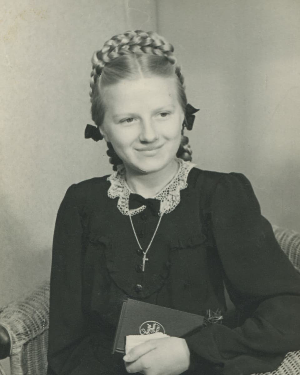 Porträt von Erna Schürch, sitzend, mit einem Büchlein in der Hand. Um ihren Kopf schlingt sich ein geflochtenes Haar.