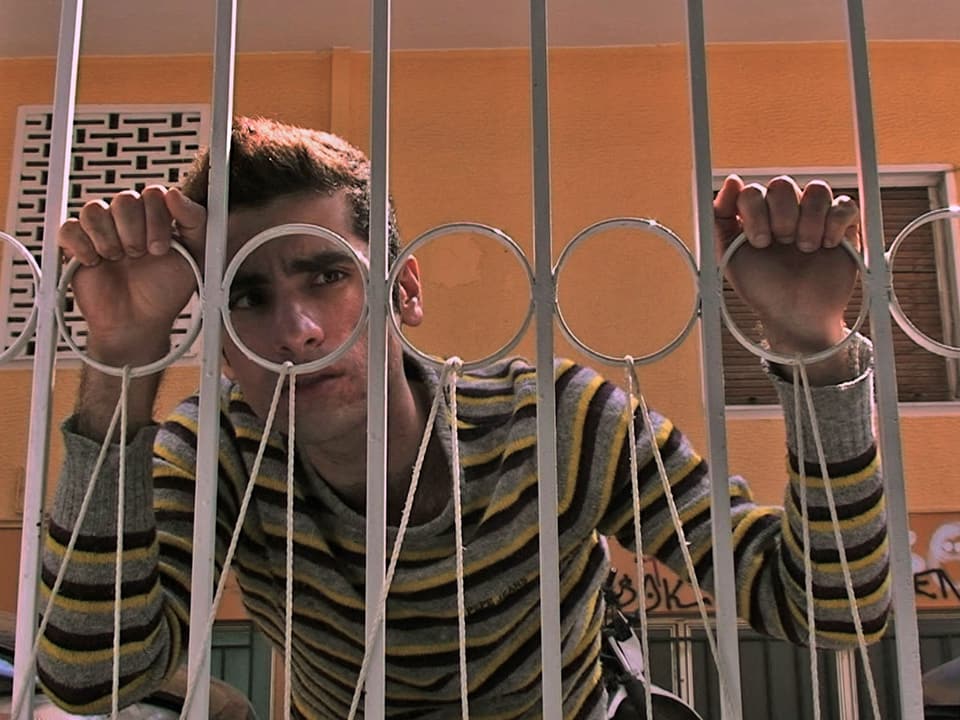 Szene aus dem Film mit einem Mann hinter einem Gitterzaun.