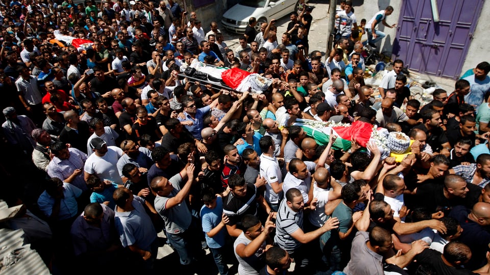 Palästinenser tragen drei mit Flaggen bedeckte Särge