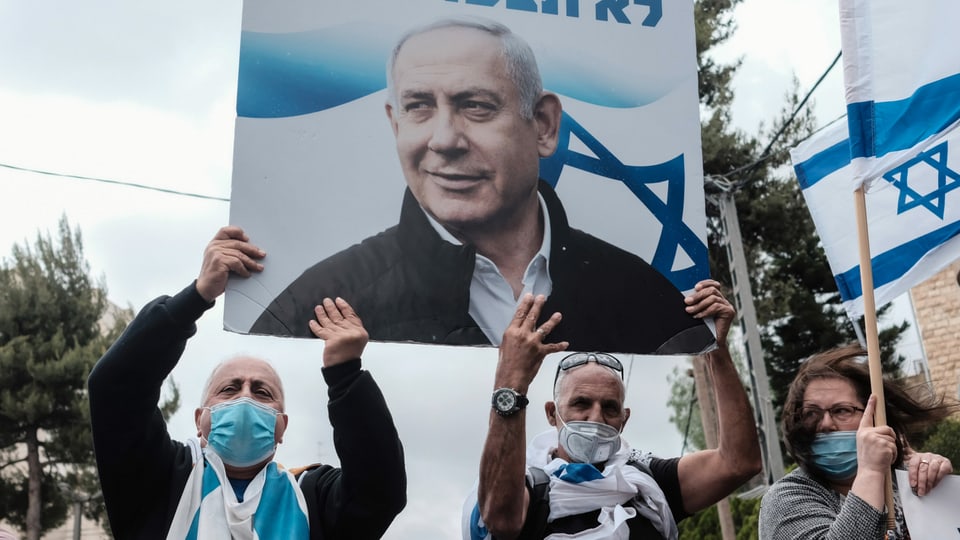 Protestierende, die ein Plakat von Netanjahu in den Händen halten.
