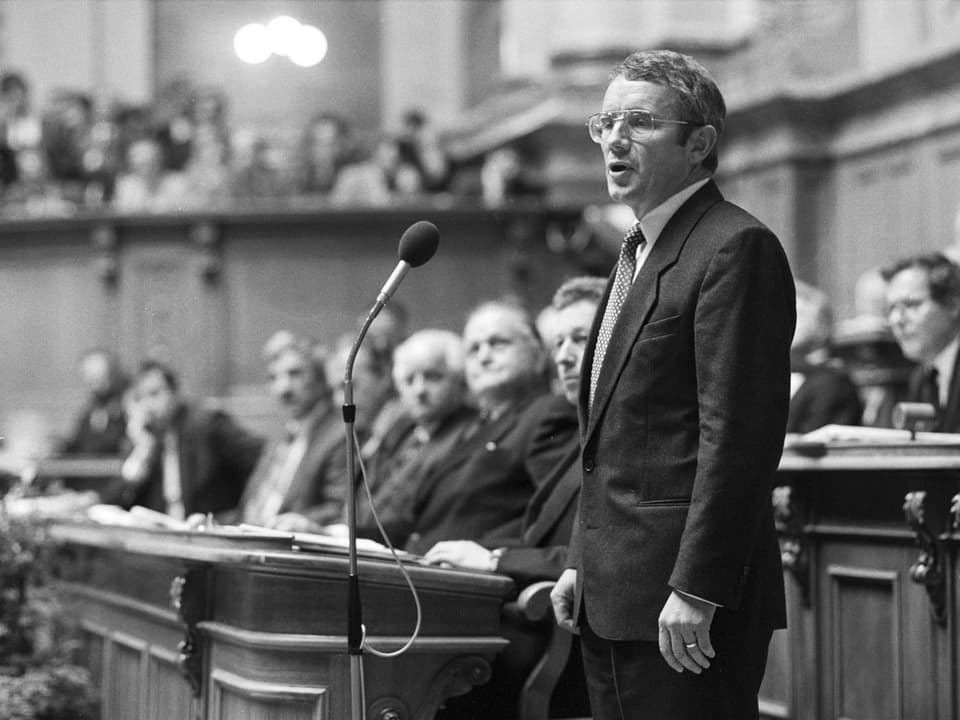 Arnold Koller steht vor Mikrofon im Parlament