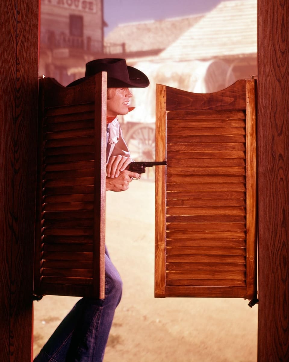 Ein Mann mit Pistole öffnet die Tür eines Salons.