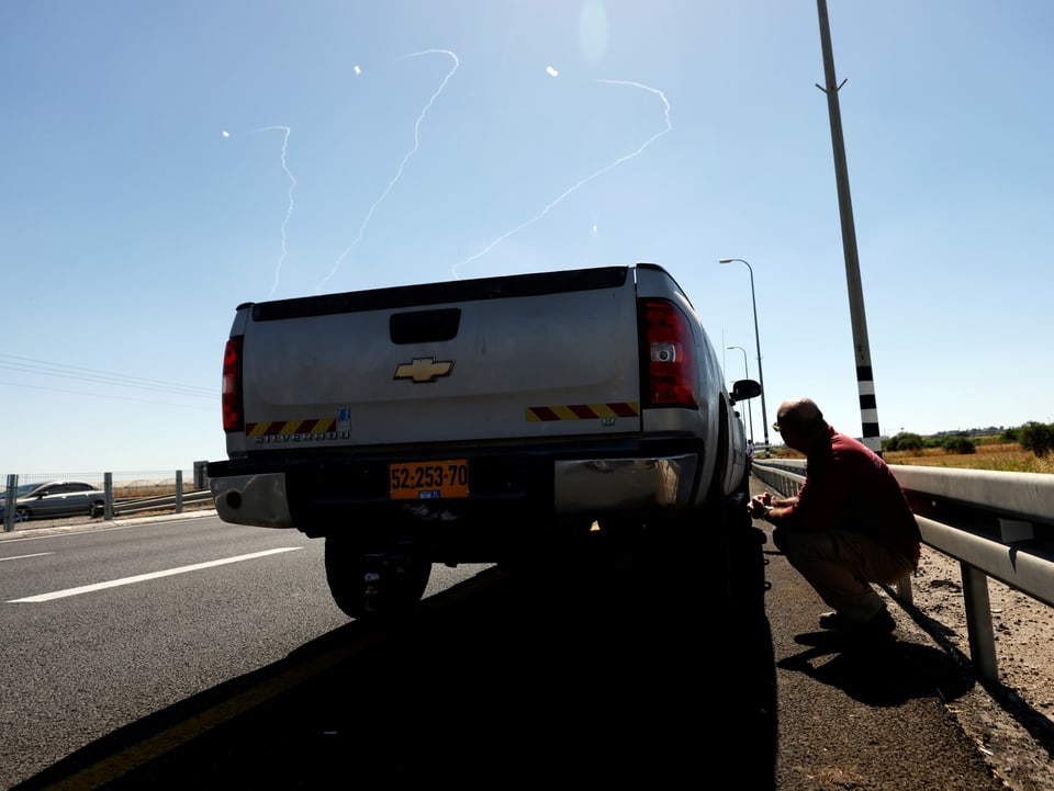 Ein Mann nimm hinter einem Auto Deckung bei einem Raketenangriff in Israel.