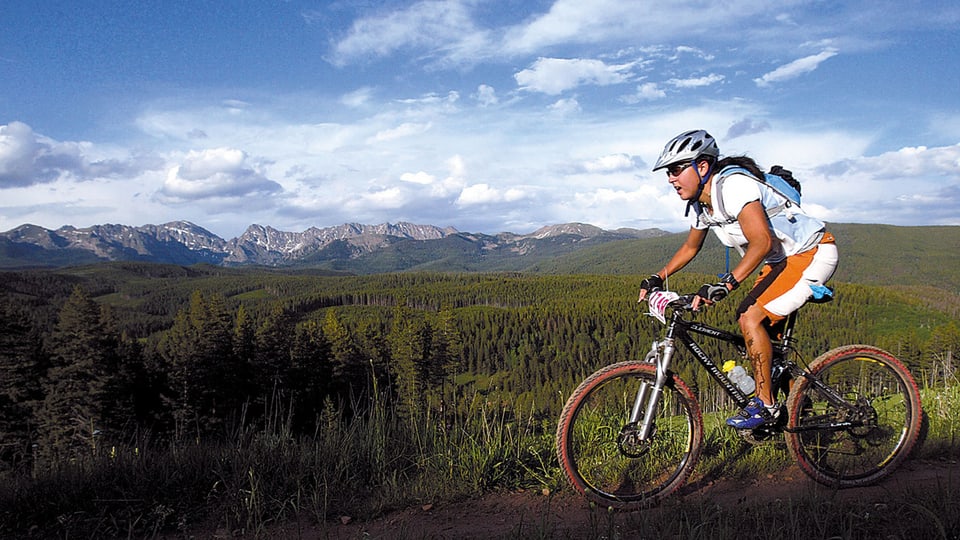 Bild einer Bikerin vor dem Hintergrund einer Bergkette.