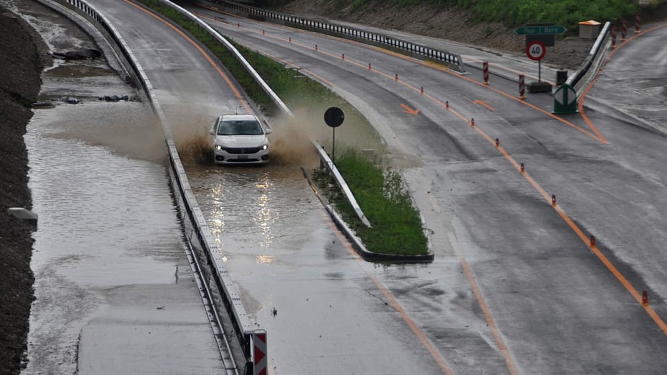 Auto fährt über eine überschwemmte Autobahn.