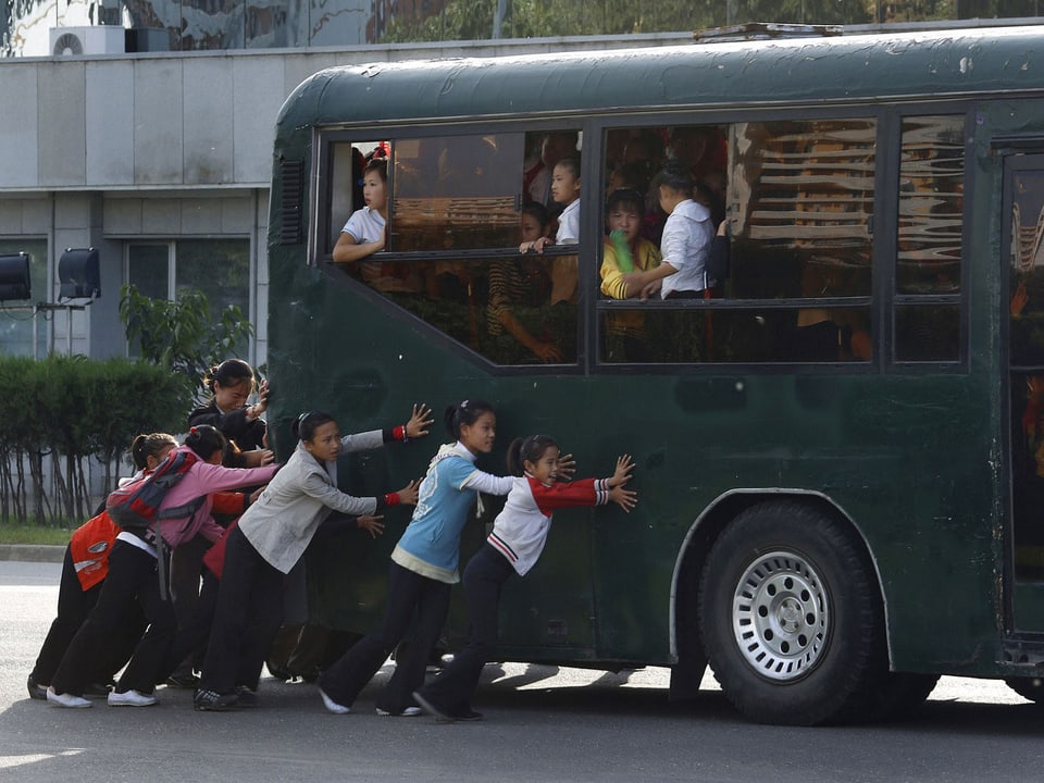 Kinder schieben einen Schulbus.
