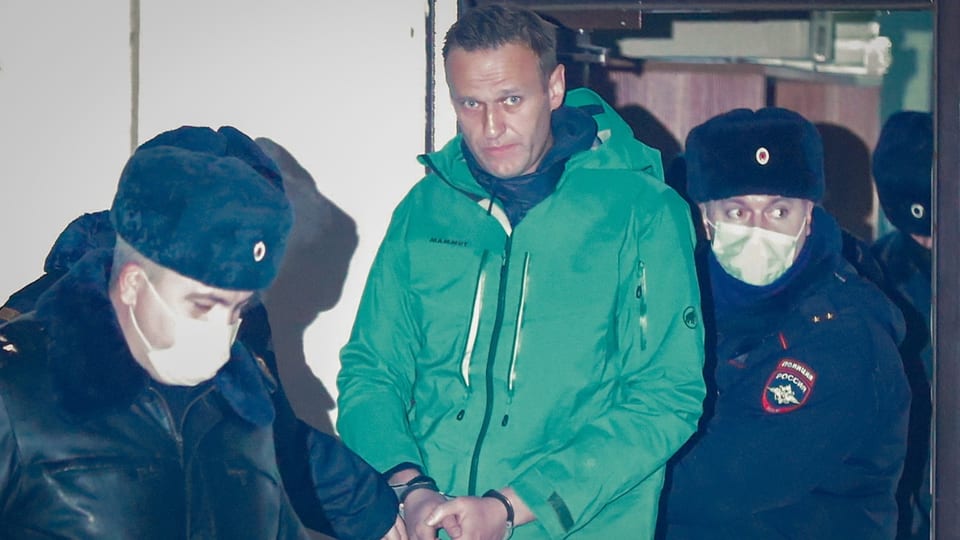 Nawalny wird in Handschellen von Polizisten abgeführt. 