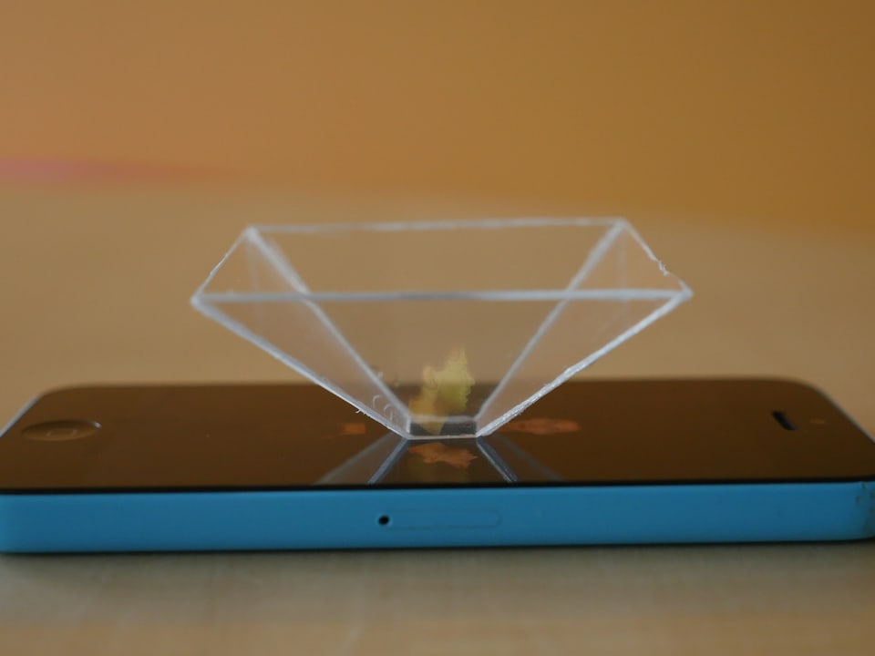 Ein selbstgebastelter Hologramm-Projektor steht auf dem Bildschirm eines Smartphones.
