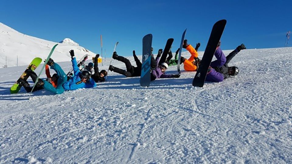 Kinder mit Snowboards liegen im Schnee