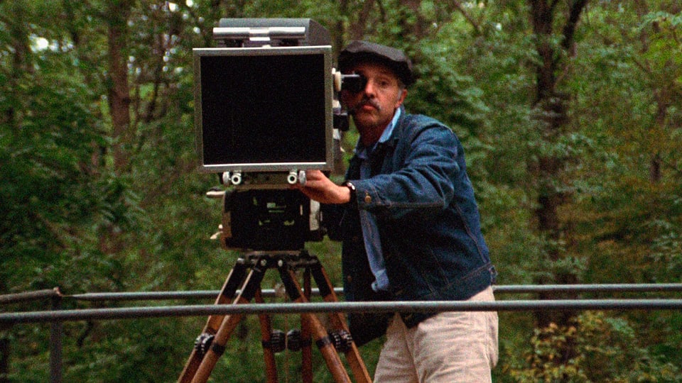 Mann im Wald mit Kamera in Richtung Zuschauer. 