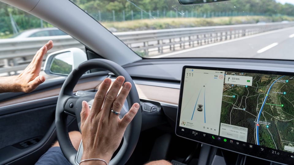 Mann fährt mit einem Tesla auf der Autobahn mit Autopilot ohne Hände am Lenkrad.