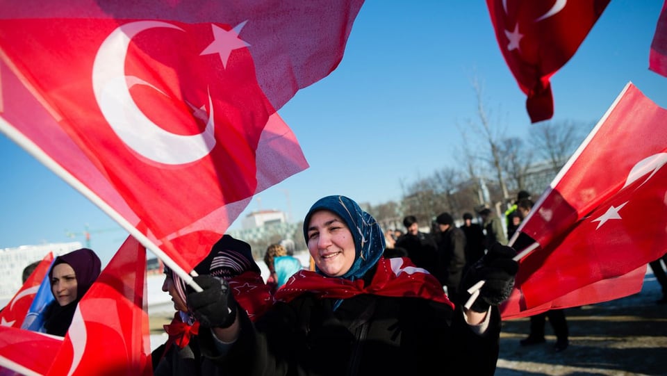 Eine Frau schwenkt mehrere türkische Fahnen.