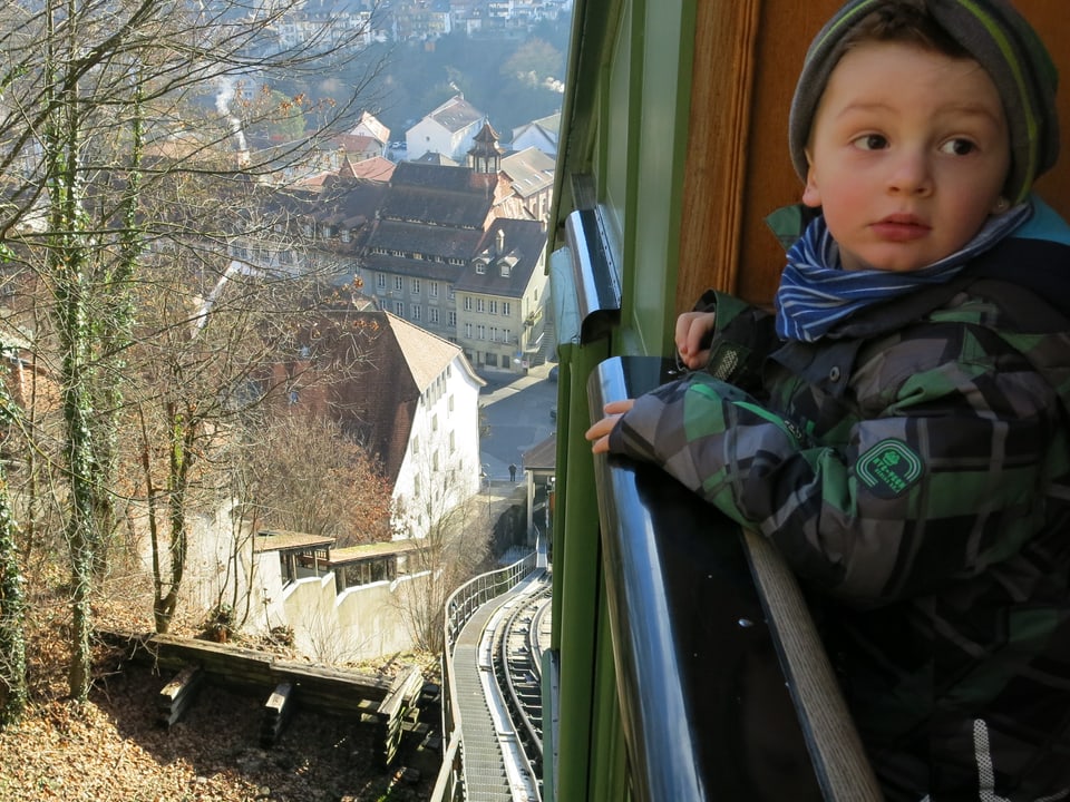 Ein kleiner Junge steht am Geländer des Funiculaire-Wagens.