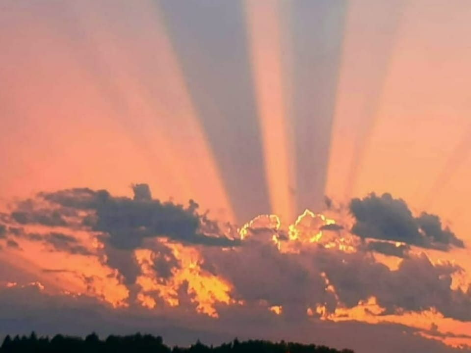 Strahlenbündel am Himmel der untergehenden Sonne.