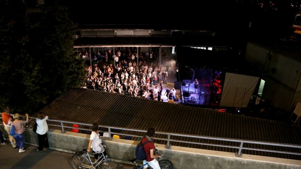Passanten blicken von der Hardbrücke hinunter zum Helsinki, wo ein Konzert über die Bühne geht.