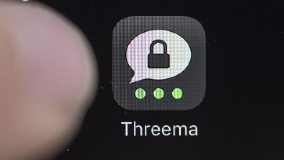 Threema-Logo auf einem Handy-Display mit einem Daumen.