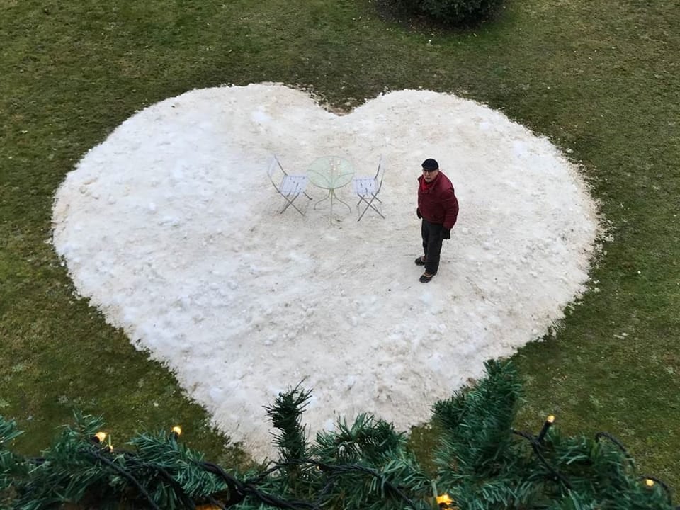 Ein Mann steht auf einem Herz aus Schnee