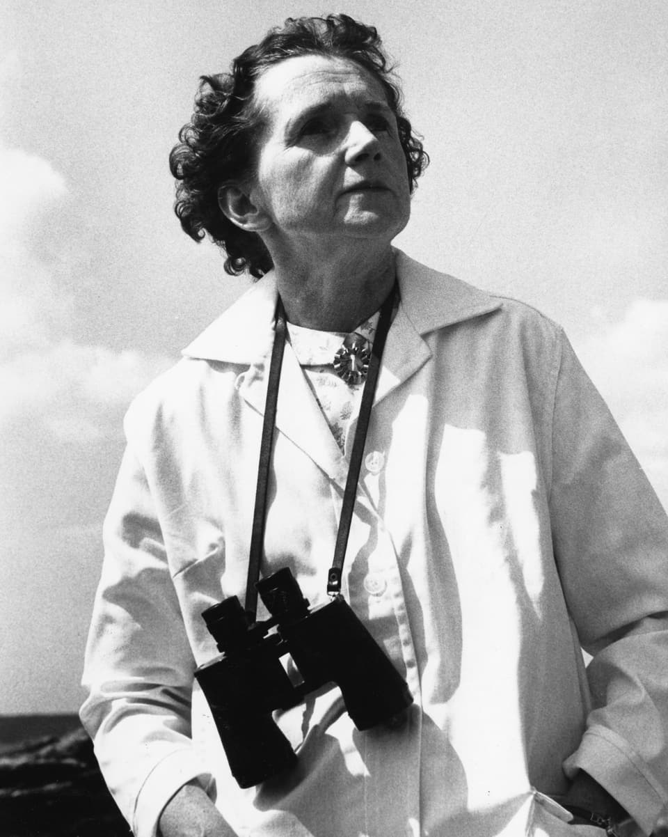 Schwarz-Weiss Bild einer Frau mit Feldstecher um den Hals hängend