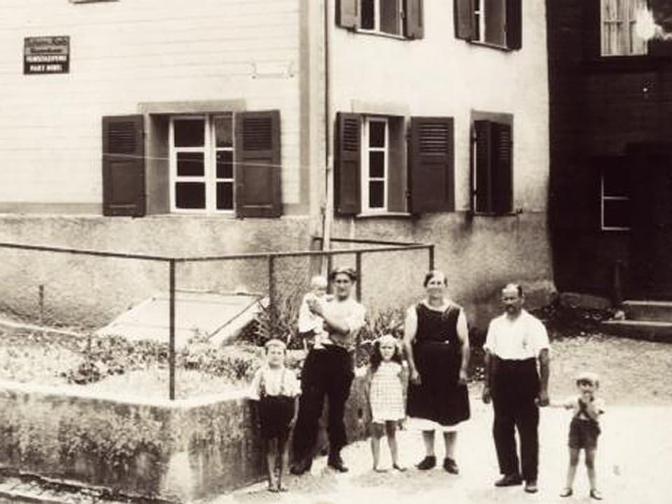 Familie vor einem Wohnhaus.