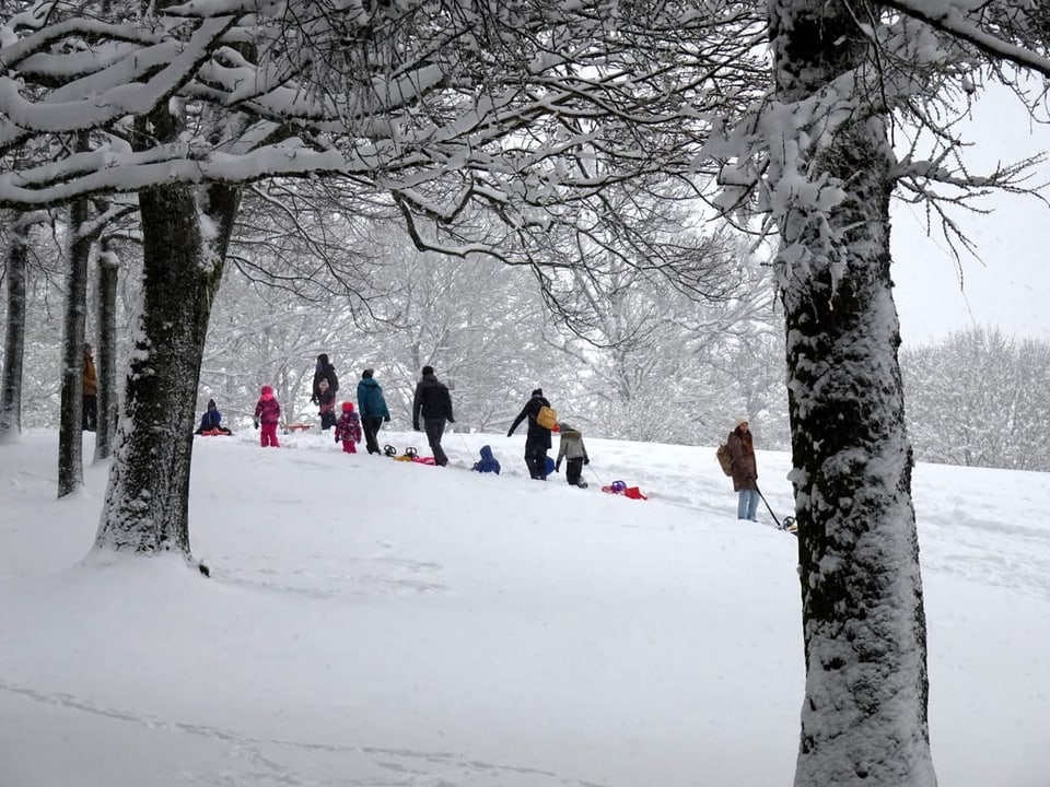 Menschen mit Schlitten im Schnee.