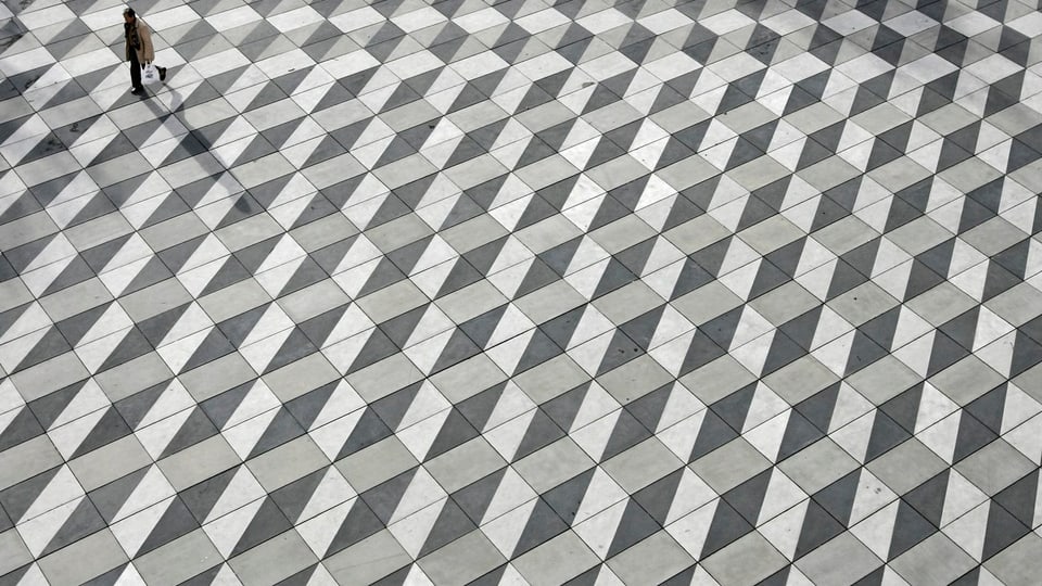 Fussgänger auf dem Max Bill Platz in Zürich Oerlikon mit geometrischem Muster.
