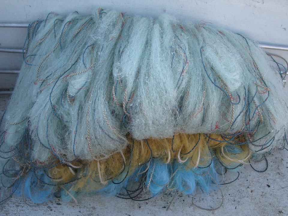 Blaues, gelbes und weisses Fischernetz zusammengelegt
