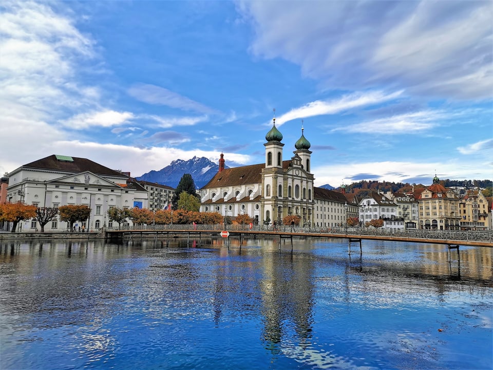 Fluss mit Häusern in Luzern bei blauem Himmel mit wenigen Wolken. 