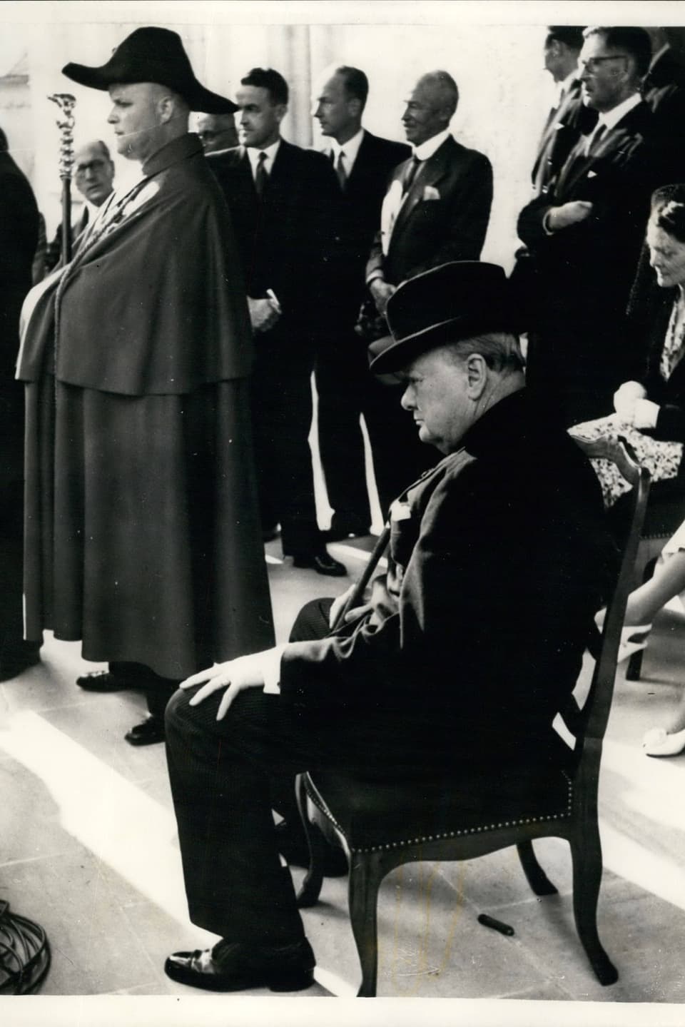Churchill sitzt auf einem Stuhl, im Hintergrund steht ein Bundesweibel.