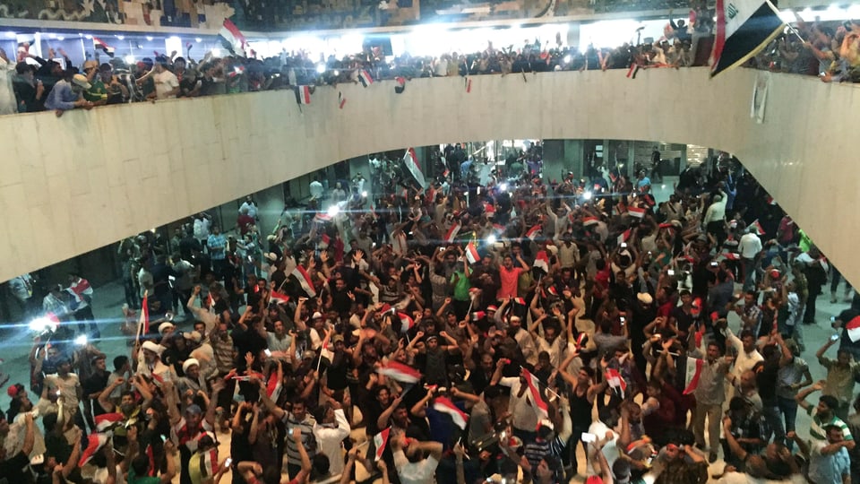 Demonstranten mit Fahnen im Parlamentsgebäude in Bagdad.