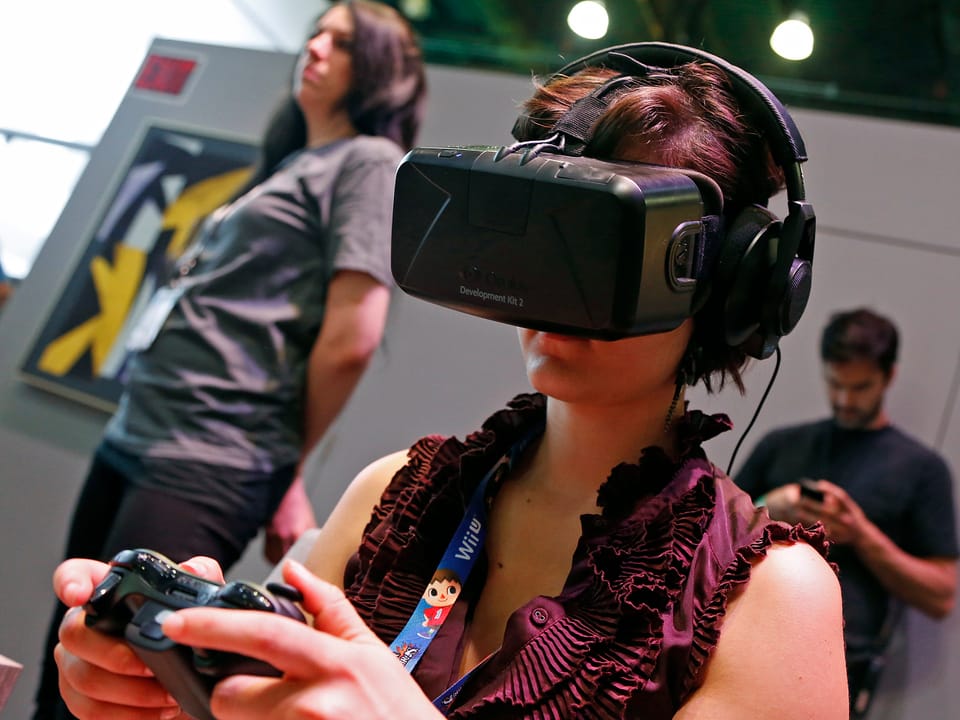 Eine Frau trägt beim Gamen eine Entwickler-Version der Oculus Rift Virtual-Reality-Brille.
