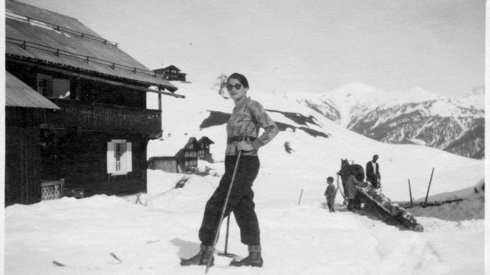 Schwarzweiss bild einer Frau auf Skiern im Schnee.